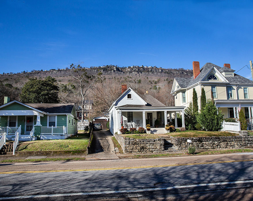 Three houses in the St. Elmo neighborhood of Chattanooga, TN sit in front of a background of mountains